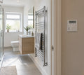 Chrome ladder towel rail in a modern UK bathroom with a digital timer fused spur mounted outside the bathroom door