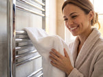 Happy woman drying hr hands with hot warm towels from chrome towel rails