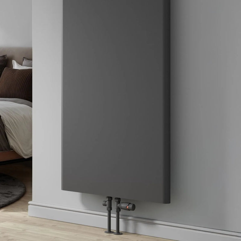 Reina Borda anthracite radiator close-up showing angled valves and floor pipework