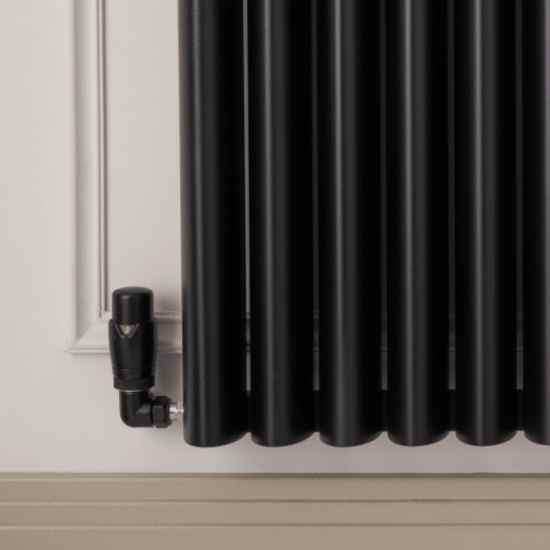 Black radiator mounted on a wall with a trv corner valve black