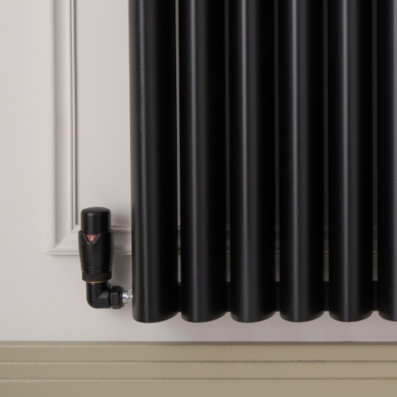 Black radiator mounted on a wall with a trv corner valve black